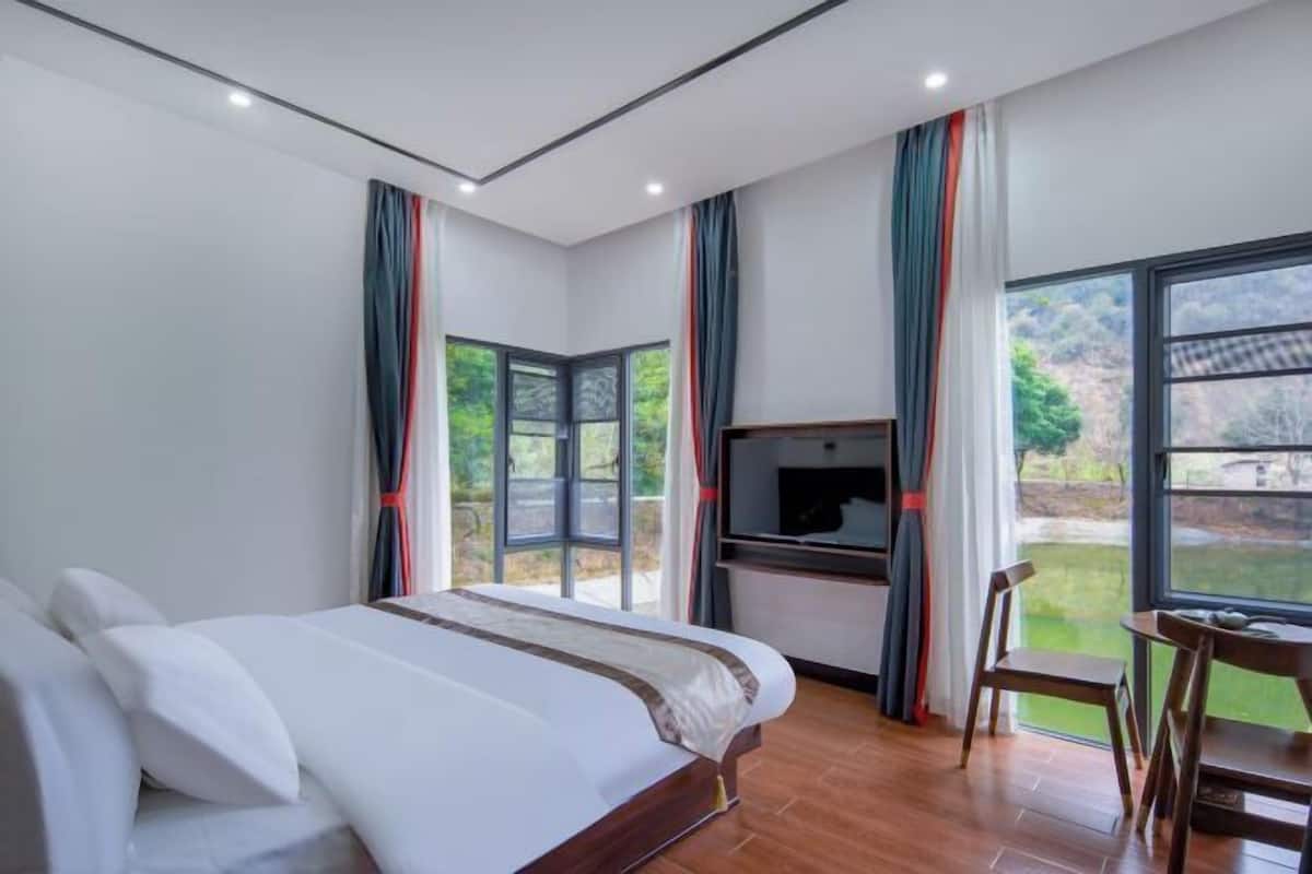 Un dormitorio con cama, televisor, escritorio y silla.