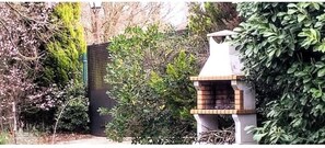 Un abreuvoir à oiseaux doté d’une base en briques et d’un dessus en bois, entouré d’un feuillage dense et d’un mur en briques.