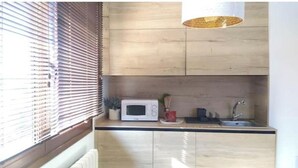 A compact kitchen with a microwave, sink, and a small potted plant.
