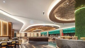 Een moderne hotelentree met een centrale bar, zitgedeeltes en een groene verticale tuin.
