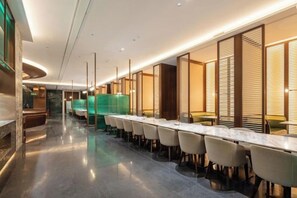 A hotel lobby with a long reception desk, seating area, and a modern design. - Changji Guesthouse (Changji)