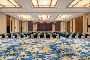 A conference room with rows of tables and chairs, a stage, and a patterned carpet. - Changji Guesthouse (Changji)