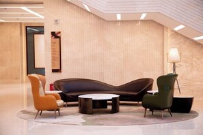 A lobby with a curved sofa, two armchairs, a round table, and a floor lamp. - Changji Guesthouse (Changji)