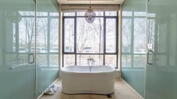 A modern bathroom with a freestanding bathtub, large windows, and glass shower doors.