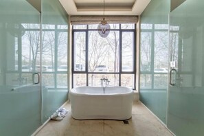 Un baño moderno con bañera independiente, ventanas amplias y puertas de ducha de vidrio.