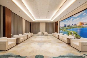 A conference room with a large carpeted floor, multiple seating arrangements, and a large window with a cityscape view. - Changji Guesthouse (Changji)