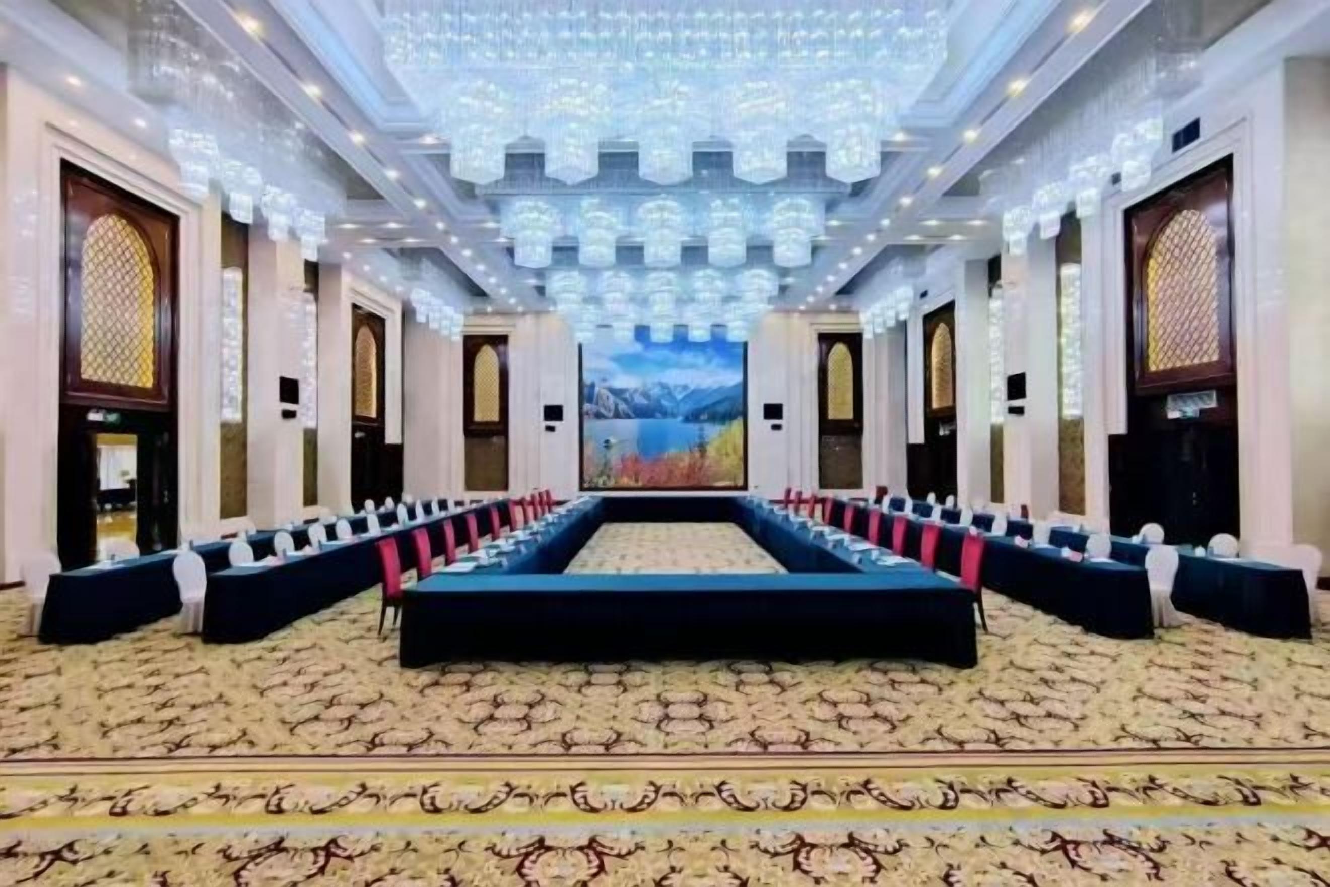 A conference room with a long table, rows of chairs, and a carpeted floor.