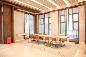 Un salón de conferencias con una mesa larga, sillas y ventanas grandes.
