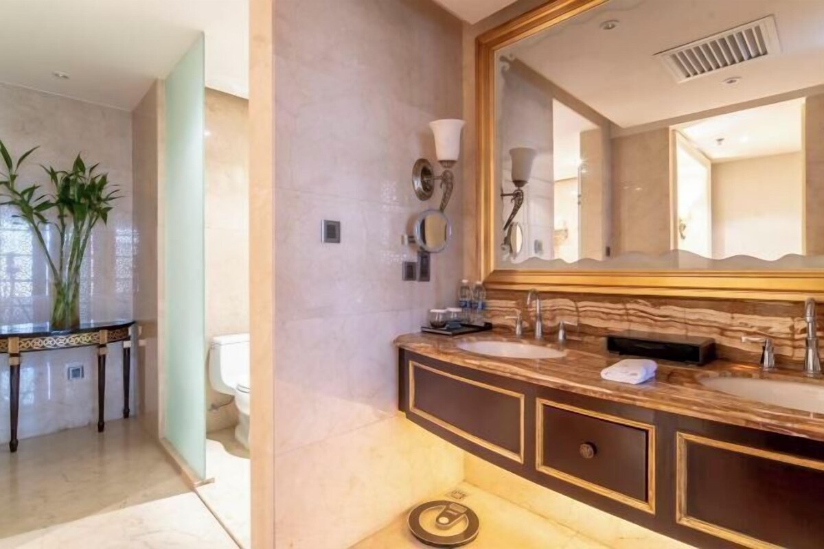Ein Badezimmer mit einem großen Spiegel, zwei Waschbecken, einer Toilette und einer Zierpflanze.