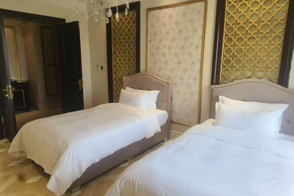 Ein Hotelzimmer mit zwei Betten, einer Kandelaber und Wandverkleidung mit Muster.