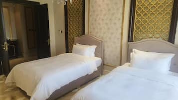 A hotel room with two beds, a chandelier, and patterned walls.