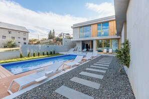 Une maison moderne dotée d’une piscine, d’un espace salon extérieur et offrant une vue sur les bâtiments voisins.