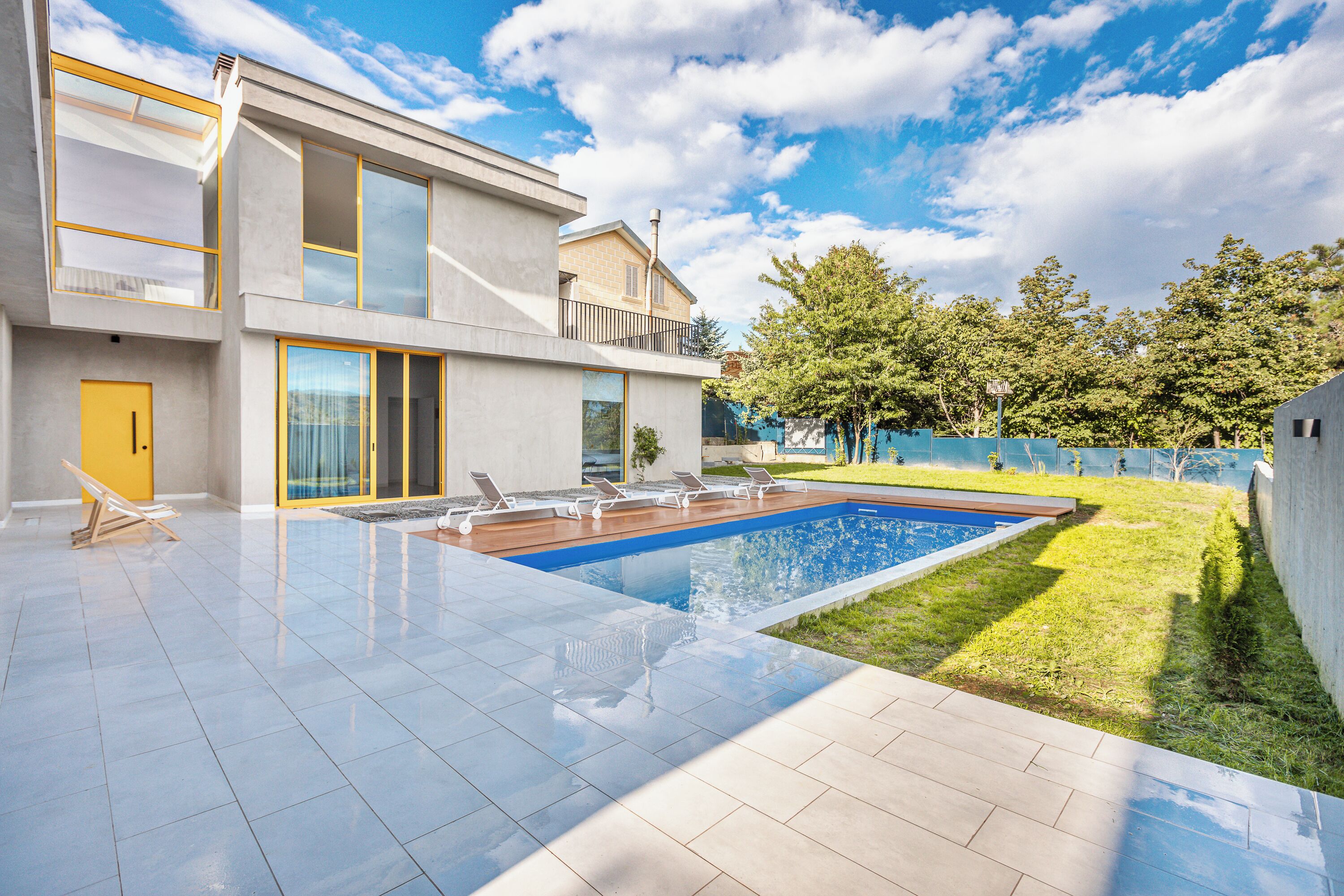 Una casa moderna de dos pisos con piscina, balcón y césped bien cuidado.