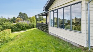 Une maison dotée d’un porche abrité, de grandes fenêtres et d’une pelouse bien entretenue.