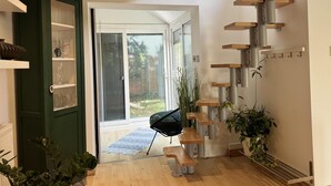 A modern interior with a wooden staircase, a green door with glass panels, and a view to the outside. - Coventry Cozy Cottage (Coventry)