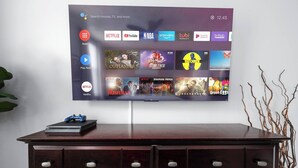 A flat-screen TV mounted on a wall displaying a streaming service interface with various content options.