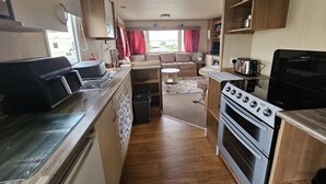 Une cuisine compacte pour camping-car, équipée d’une cuisinière, d’un évier et d’un petit coin repas.