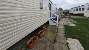 Une rangée de maisons mobiles, avec un chemin pavé et des plantes en pot.