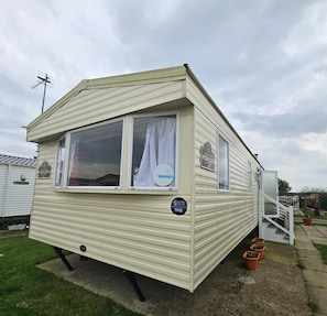 A mobile home with a window, a door, and a small staircase leading to the entrance. - Caravan Lynne 3 bed Robin Hood (Rhyl)