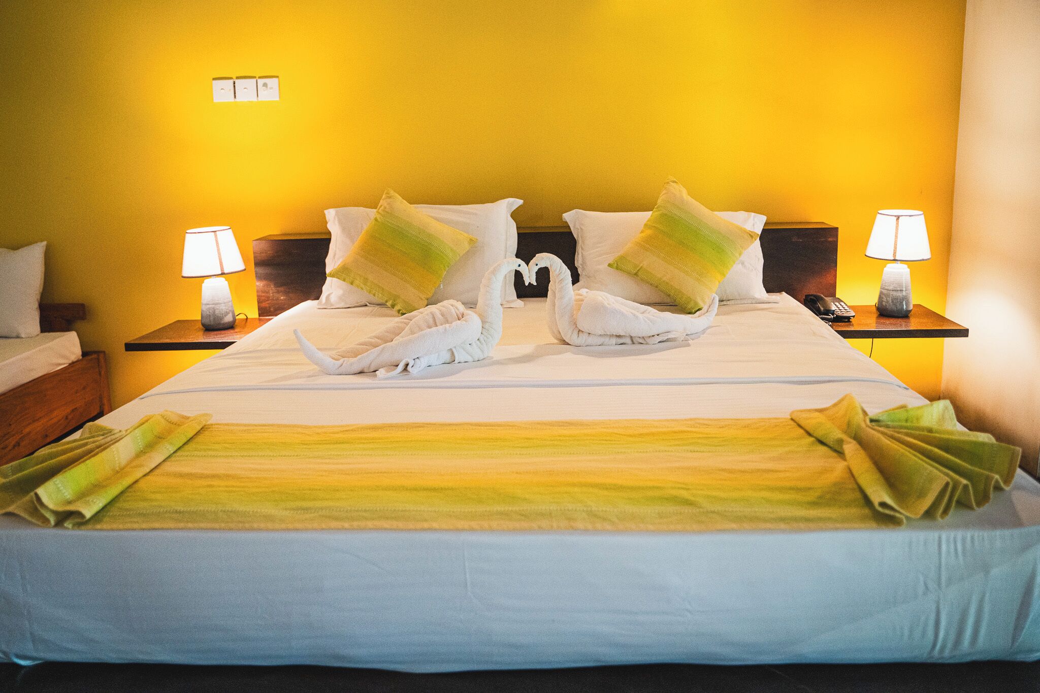 Une chambre d’hôtel avec un lit, deux tables de chevet et une lampe de chaque côté.