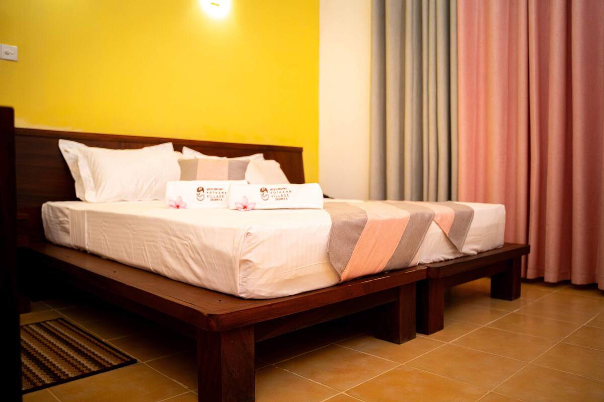 Cama de casal com roupa de cama branca e cabeceira de madeira, mesa de cabeceira e luminária fixada na parede.