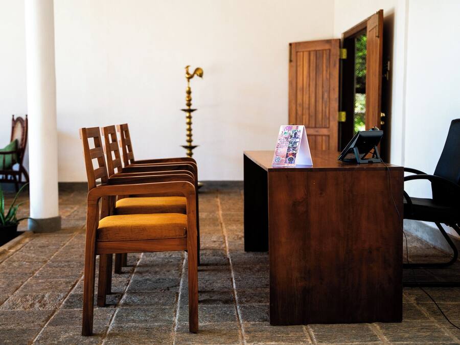 A reception area with a wooden desk, a black office chair, and a wooden chair with a cushion.