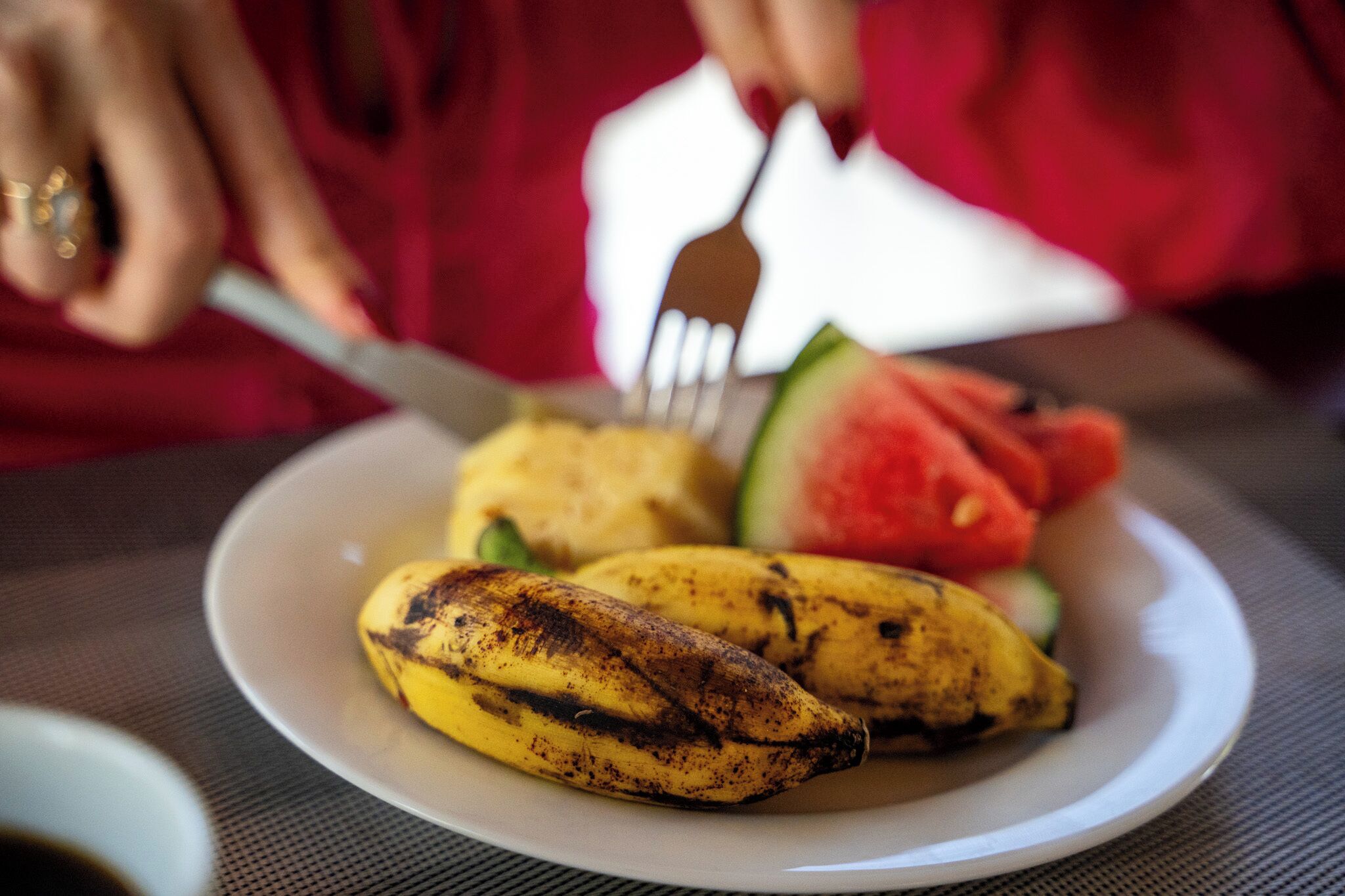 Un plato con una banana, una tajada de sandía y un tenedor.