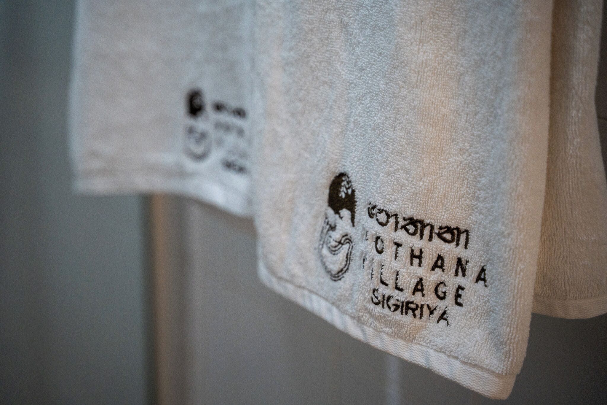 A towel with embroidered text indicating it is from Othana Village in Sigiriya.