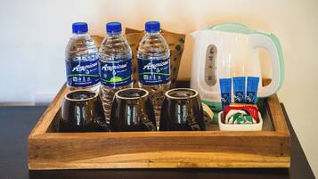 Una bandeja de madera con botellas de agua estadounidense, una taza blanca y sobres de té o café.