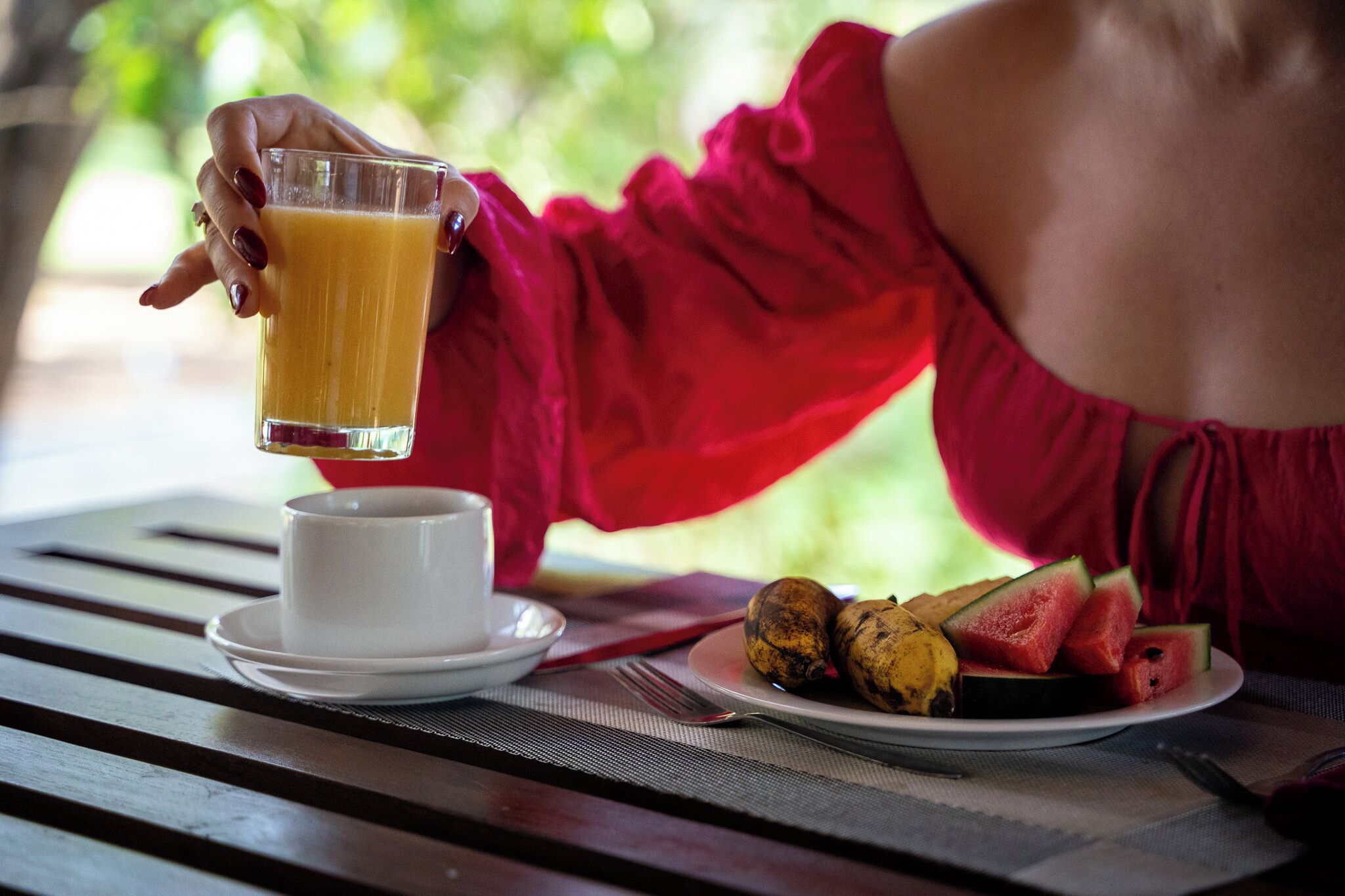 Una mesa de comedor con un plato de comida, un vaso de jugo de naranja y una taza.