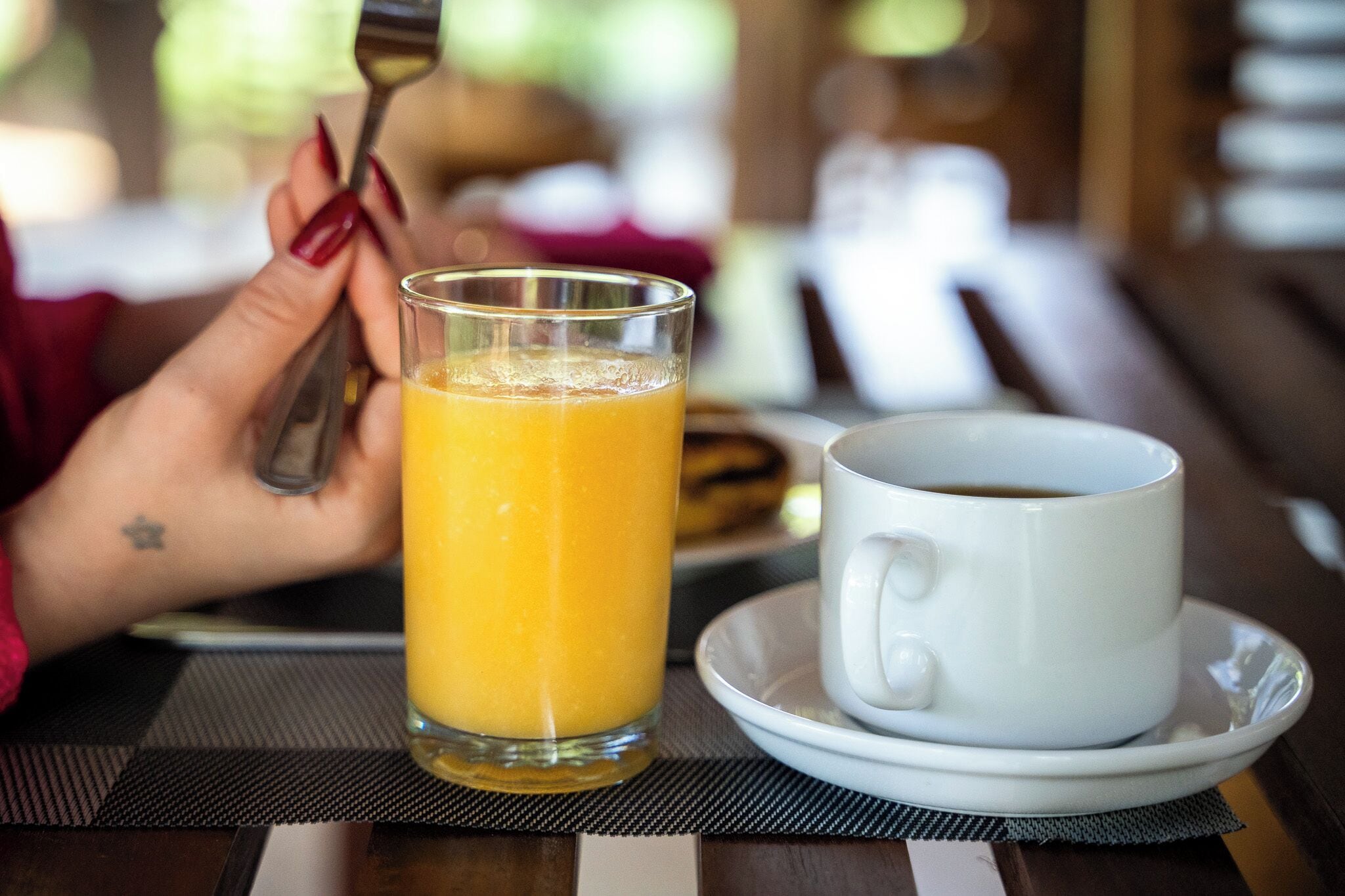 A glass of orange juice and a cup of coffee on a table with a placemat.