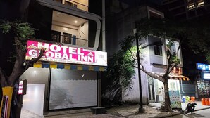 A hotel with a prominent sign, a closed shutter, and a parked motorcycle. - Hotel Global Inn (Indore)