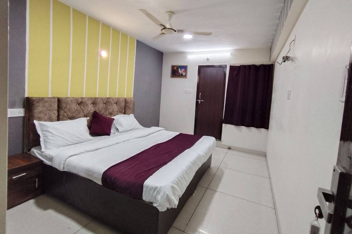 A bedroom with a bed, nightstand, ceiling fan, and a door.
