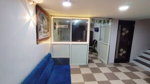A reception area with a checkered floor, a blue sofa, a reception desk, and a sign that reads "RECEPTION". - Hotel Global Inn (Indore)