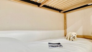A single bed with a wooden headboard and a small stuffed animal on the bed.