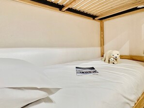 A single bed with a wooden headboard and a small stuffed animal on the bed.