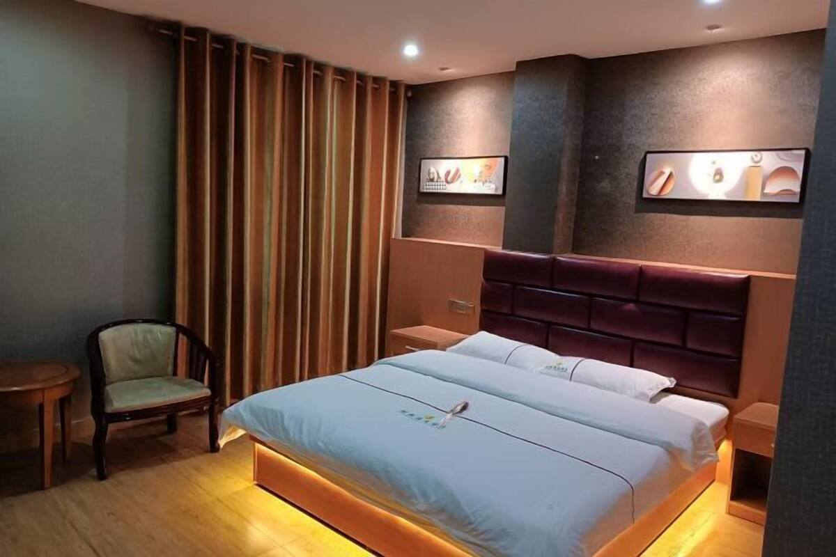Une chambre d’hôtel avec un lit, une chaise, une table de chevet et un tableau accroché au mur.
