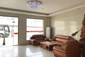 A spacious lobby with leather sofas, a coffee table, and a chandelier. - Youshang Boutique Hostel (Dongguan)