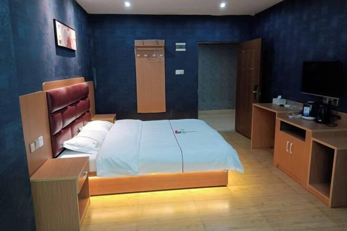 Une chambre d’hôtel comprenant un lit, une armoire en bois, une télévision et une petite table avec une machine à café.
