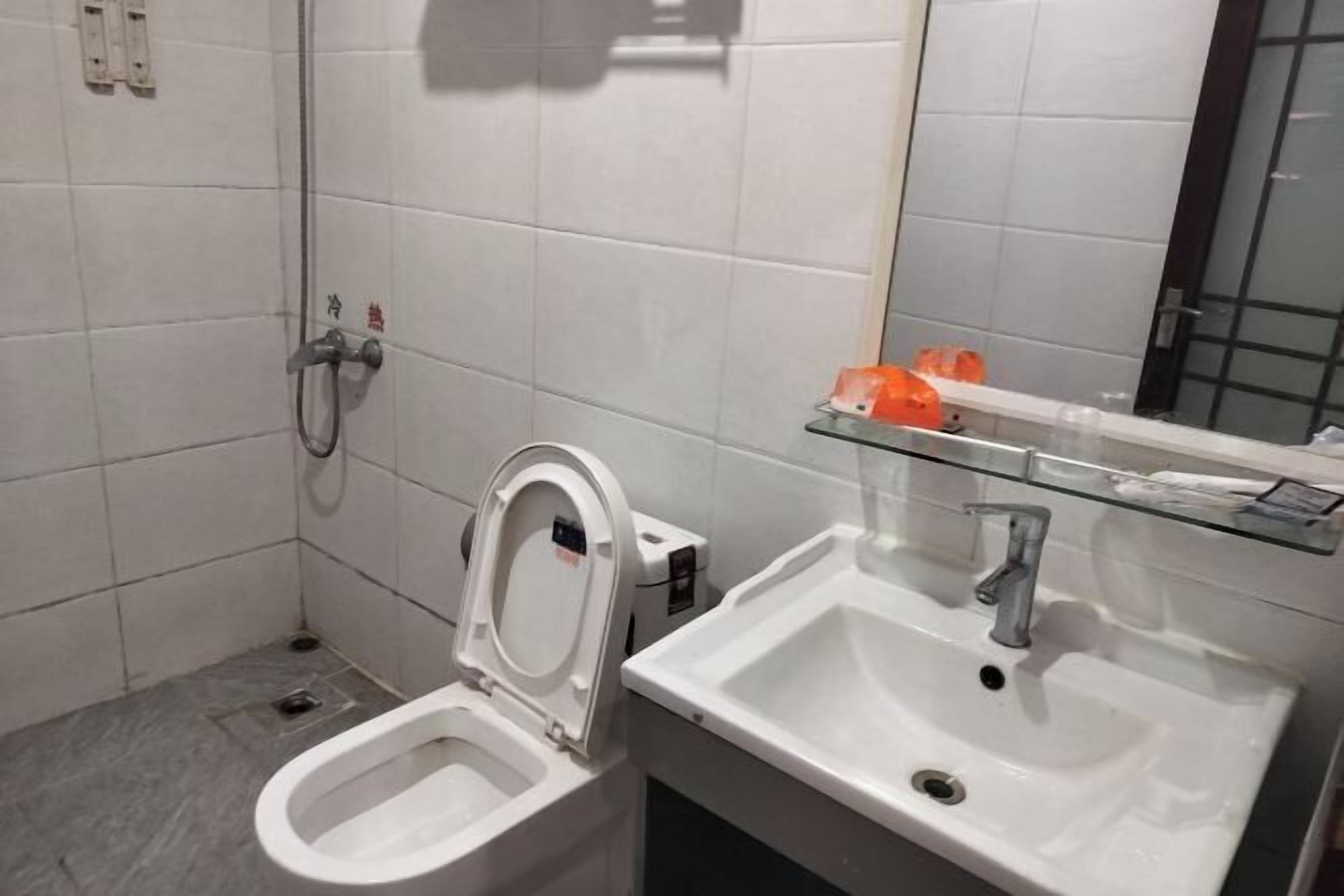 Een badkamer met toilet, wastafel en glazen plank met toiletartikelen.