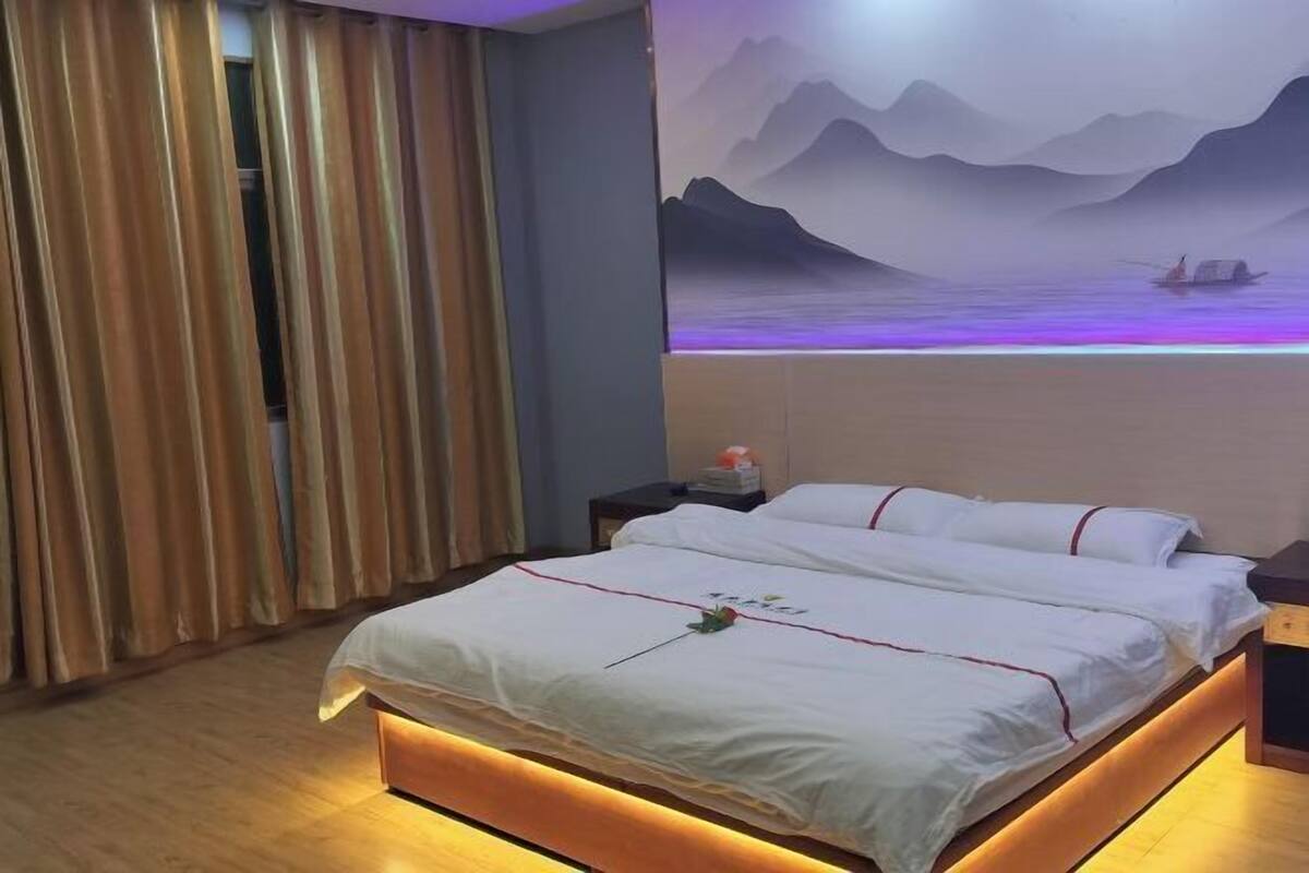 Une chambre d’hôtel avec un lit, des rideaux, une table de chevet et une fresque murale.