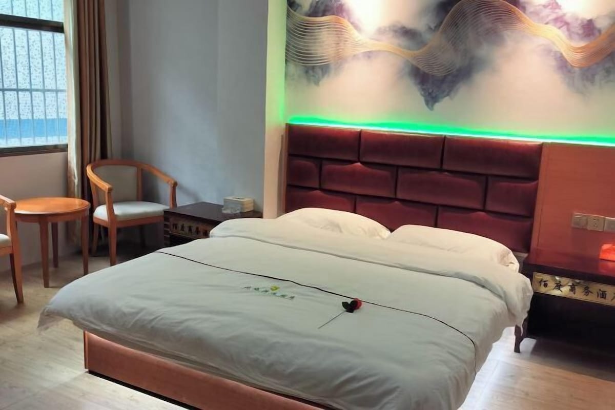 Habitación de hotel con cama, una silla, un escritorio y una pared con un detalle decorativo de iluminación.
