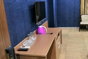 A wooden table with a remote control, a pink kettle, and a glass container. A television is mounted on the wall above the table. - Youshang Boutique Hostel (Dongguan)