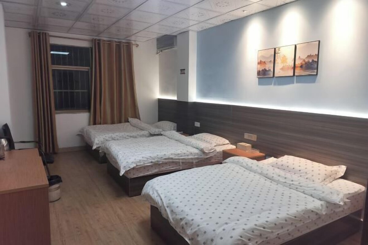 Una habitación de hotel con dos camas, un escritorio y una ventana con cortinas.