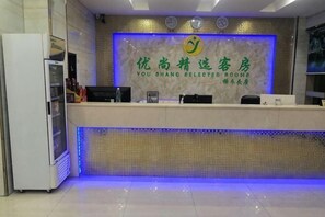 A reception desk with a tiled wall, a logo, and a digital clock.