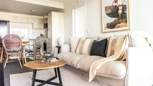 A living room with a sofa, coffee table, wicker chairs, and a framed picture on the wall.