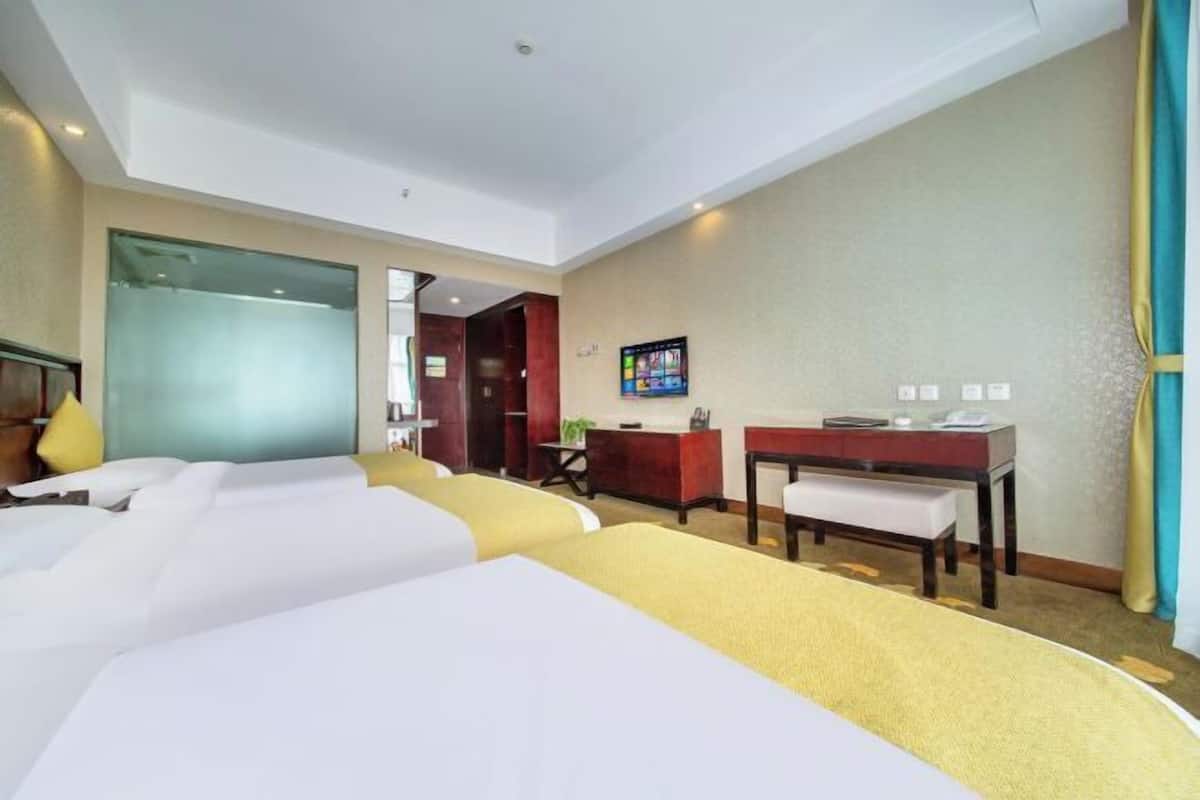 A hotel room with two beds, a desk, a chair, and a television.