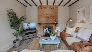 Una sala de estar con chimenea de ladrillo, televisor, sofá y mesa de centro.