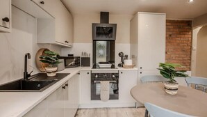 Una cocina moderna con armarios blancos, una estufa negra y un comedor con mesa y sillas.