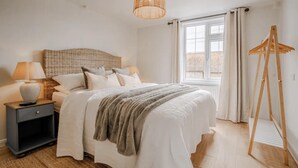 A bedroom with a bed, bedside table, lamp, and a window with curtains. - Coastal/petsok/kingbed/wifi/garden (Driffield)